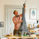 A man putting the top section on the Lego Eiffel Tower set.